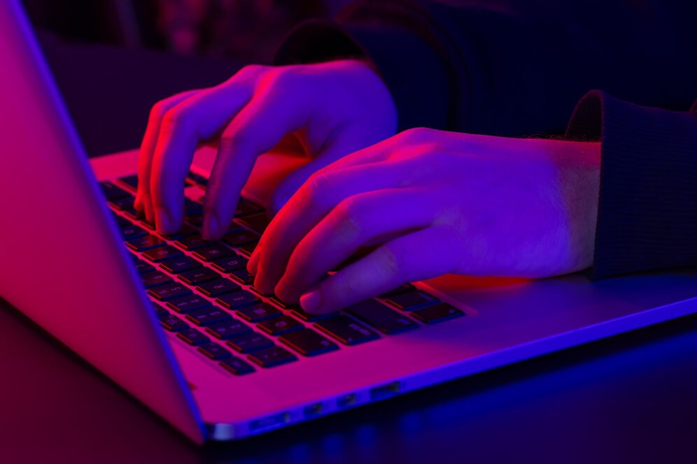 un-uomo-usa-le-mani-maschili-del-primo-piano-del-computer-portatile-nell-illuminazione-al-neon_16901